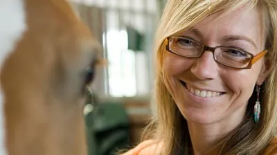 Katharina Winterkamp lächelt neben einem Pferd